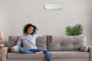 woman on couch enjoying central air conditioning